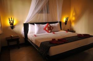 a bedroom with a large bed with two lights at Tirta Sari Bungalow in Pemuteran
