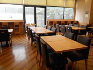 a restaurant with wooden tables and chairs and windows at Hotel Route-Inn Nagoya Higashi Betsuin in Nagoya