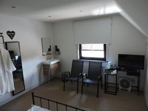 een woonkamer met 2 stoelen, een tafel en een raam bij B&B Carpe Diem in Maaseik