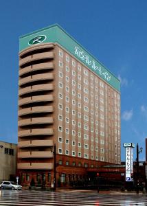 a large building with a sign on the top of it at Hotel Route-Inn Kushiro Ekimae in Kushiro