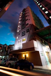 a tall building with cars parked in front of it at Swiss Hotel Apartment in Kuala Belait