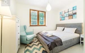 a bedroom with a bed and a blue chair at Wonder Home - Apartamenty Leśny Dom z balkonami, niedaleko centrum, w cichej okolicy in Karpacz