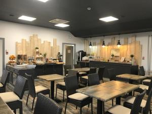 a restaurant with wooden tables and chairs and a counter at Kyriad Direct Agen in Castelculier