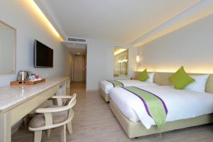 a hotel room with two beds and a desk at Hisea Huahin Hotel in Hua Hin