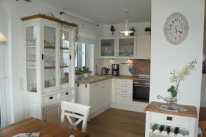 ベルガーエンデ・レートヴィッシュにあるReethaus Casa Balticaの白いキャビネットと木製テーブル付きのキッチン
