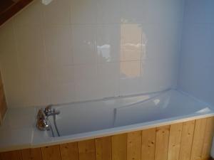 una vasca da bagno in una camera con parete piastrellata di Les brimbelles a Gérardmer
