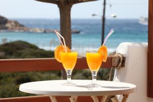 dos vasos de jugo de naranja en una mesa con el océano en Maistrali, en Galissas