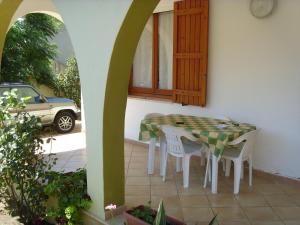un tavolo e sedie su un patio con finestra di villletta indipendente a 300 metri dal mare a Solanas