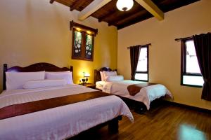 1 Schlafzimmer mit 2 Betten und 2 Fenstern in der Unterkunft Puri Sakanti Nature Family Resort in Ciwidey