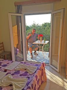 een man aan een tafel buiten een raam bij Acapoulco apartments in Anaxos