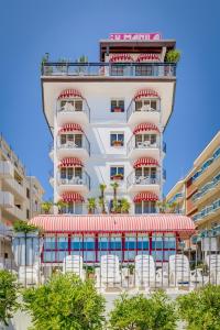 a tall white building with chairs in front of it at Hotel Manila in Lido di Jesolo
