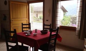 a table with a red table cloth and chairs and a window at Il Pesco in Nus