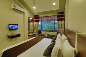 a hotel room with a bed and a television at Highland Resort in Lonavala