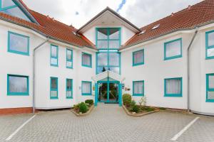 a large white building with a blue door at Montana Trend Hotel Lehrte in Lehrte