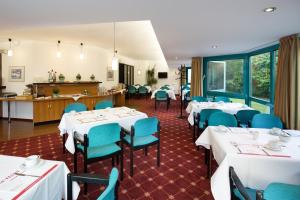 un comedor con mesas blancas y sillas azules en Montana Trend Hotel Lehrte en Lehrte
