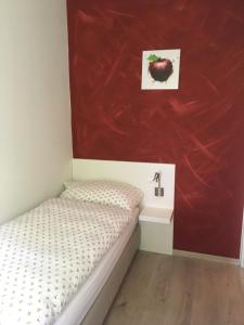 a small bedroom with a bed and a red wall at B&B Tencia in Prato