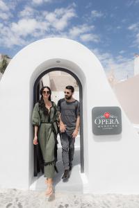 a man and a woman walking out of a door at Opera Mansion Santorini in Fira