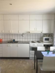 een keuken met witte kasten, een tafel en een fornuis bij Kungshamns Vandrarhem in Kungshamn
