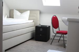 a bedroom with a bed and a red chair at Gästehaus Hubertushof - 24h Check-In in Hausen