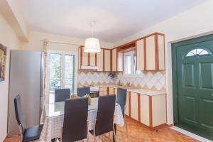 a kitchen with a table and chairs and a green door at Vafkeri Apartments in Vavkerí