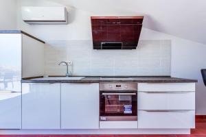 una cocina con armarios blancos y fregadero en Apartments Host, en Rab