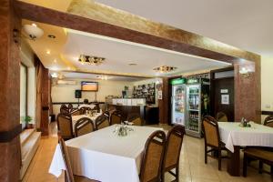カリマネシュティにあるPensiunea Alfridの白いテーブルと椅子のあるレストラン、バー