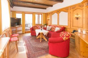 a living room with two red chairs and a table at Hotel Alte Krone in Mittelberg