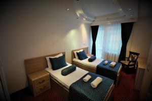 Habitación pequeña con 2 camas y ventana en Hotel Pejton, en Pristina