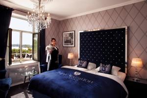 a woman standing next to a bed in a room at Hotel Wassilioff - Unike Hoteller in Stavern