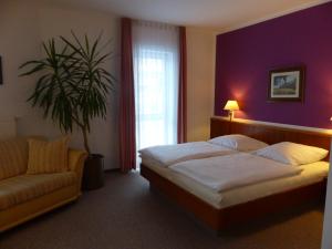 ein Schlafzimmer mit einem Bett und einem Sofa und einer Pflanze in der Unterkunft Hotel Dorotheenhof in Cottbus