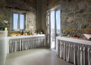 a kitchen with two sinks and a stone wall at Lithos Luxury Rooms (Adults Only) in Adamantas
