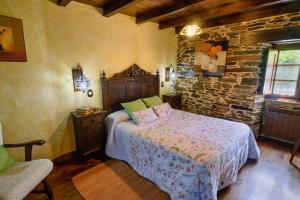 a bedroom with a bed and a stone wall at Casas da Lexa in Taramundi