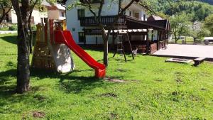 una diapositiva roja en un patio junto a una casa en Gostišče Hedvika en Kal-Koritnica