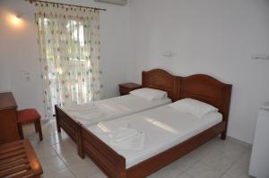 Hotel Dougas في أركودي: غرفة نوم بسرير وملاءات بيضاء ونافذة