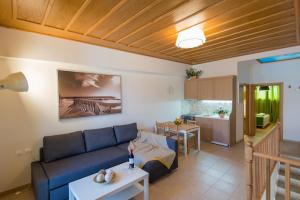 a living room with a blue couch and a kitchen at Castello Di Porto in Panormos Rethymno