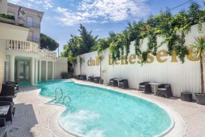 einen Pool mit Stühlen und ein Gebäude in der Unterkunft Hotel Mediterraneo Club Benessere in Bellaria-Igea Marina