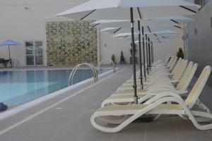 uma fila de espreguiçadeiras com guarda-sóis ao lado de uma piscina em Golden Tulip Le Diplomate em Cotonou