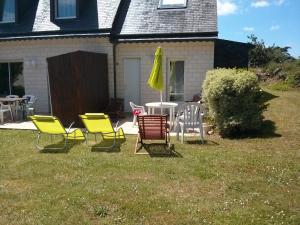 a group of chairs and a table with a yellow umbrella at Chez Loly in Trébeurden