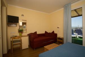 a room with a bed and a couch and a table at Albergo Vittoria in Rimini