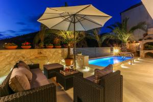 赫瓦爾的住宿－Villa Capitis in the center - Apartment with private pool，游泳池旁的天井配有椅子和遮阳伞。