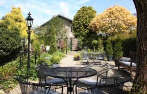 un patio con tavoli e sedie in giardino di Walnut Lodge Bed & Breakfast a Noorbeek