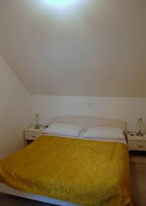 a bedroom with a bed with a yellow blanket on it at Villa Violić in Zaton