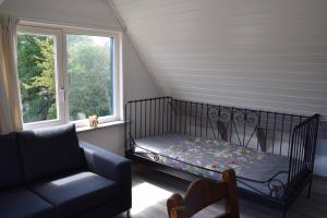Una cuna en una habitación con sofá y ventana en Strandleven, en Goote Keeten