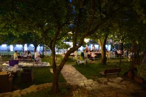 un grupo de personas sentadas en mesas en un parque por la noche en Heybeli Hotel, en Mudanya