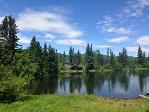 a lake with a house in the middle of it at Le Ross - Les Chalets Spa Canada in La Malbaie