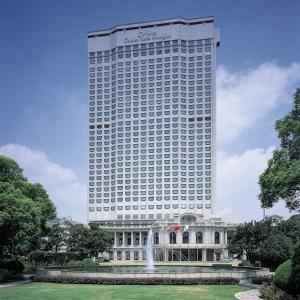 ein hohes Gebäude mit einem Brunnen vor einem Gebäude in der Unterkunft Okura Garden Hotel Shanghai in Shanghai