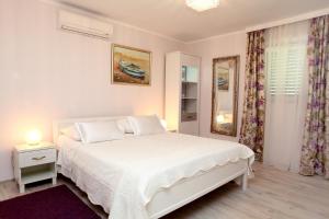 ein weißes Schlafzimmer mit einem Bett und einem Spiegel in der Unterkunft Villa Rustica Dalmatia in Seget Vranjica