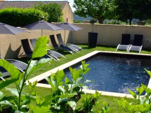 a pool with chairs and umbrellas in a yard at MAISON DE MARQUAY-MAISON D'HOTES in Marquay