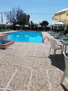 a swimming pool with chairs and tables and umbrellas at La Piscina in Marina di Massa