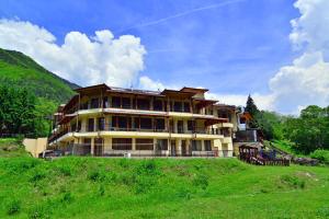 a large building on top of a grassy hill at Family Hotel Gorski Kut in Rilski Manastir